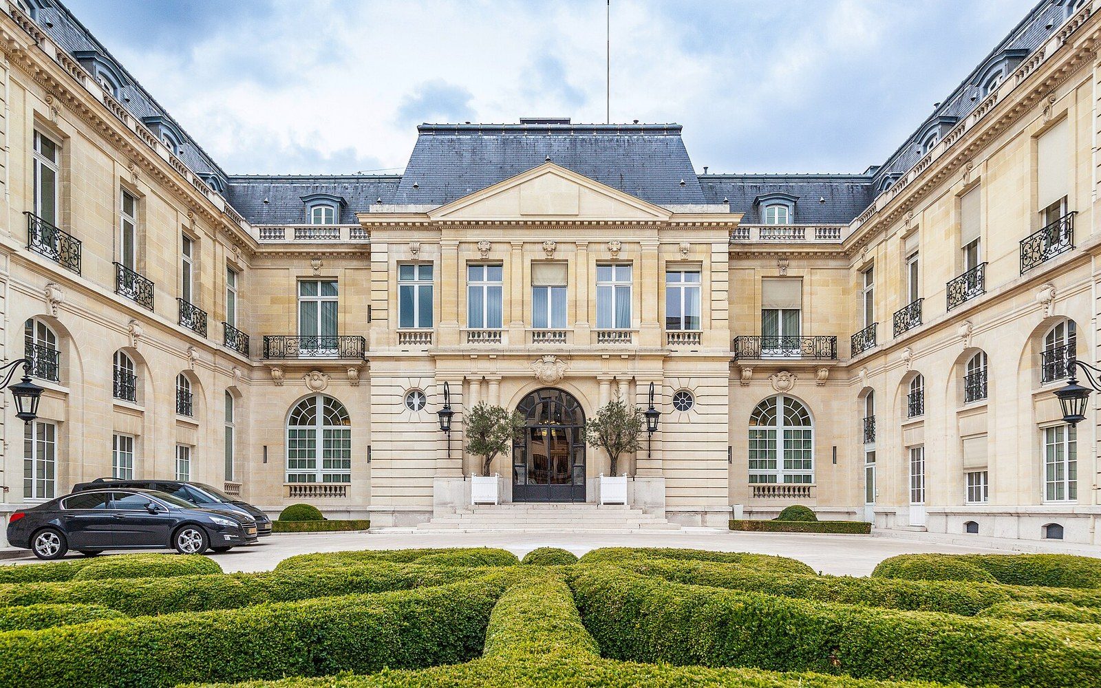 Château de la Muette's mansard-roofed facade overlooks manicured hedges and a parked car
